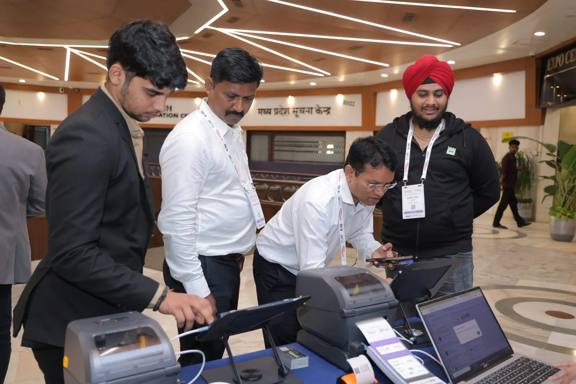 Staff scanning a guest's QR pass while the badge prints at the EDEC 2026 arrival desk